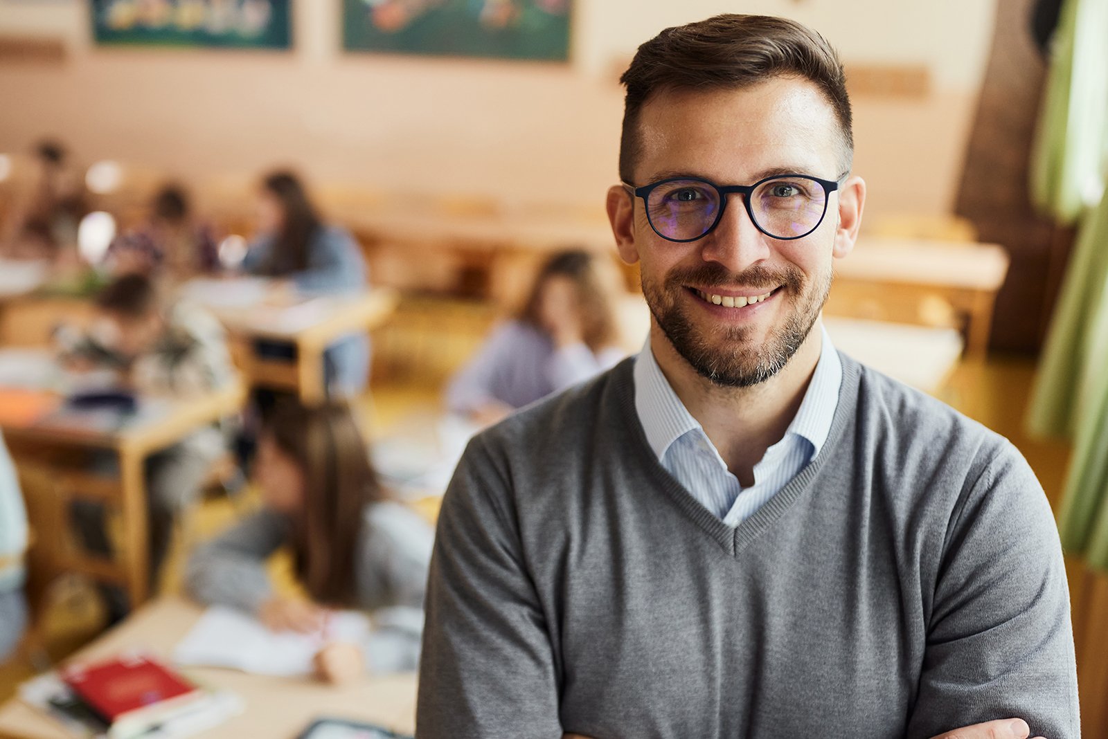 Young male teacher with thing black frames smiling